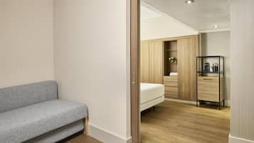 Quarto moderno com um sofá cinzento, um guarda-roupa de madeira e uma mesa de cabeceira com uma chaleira.