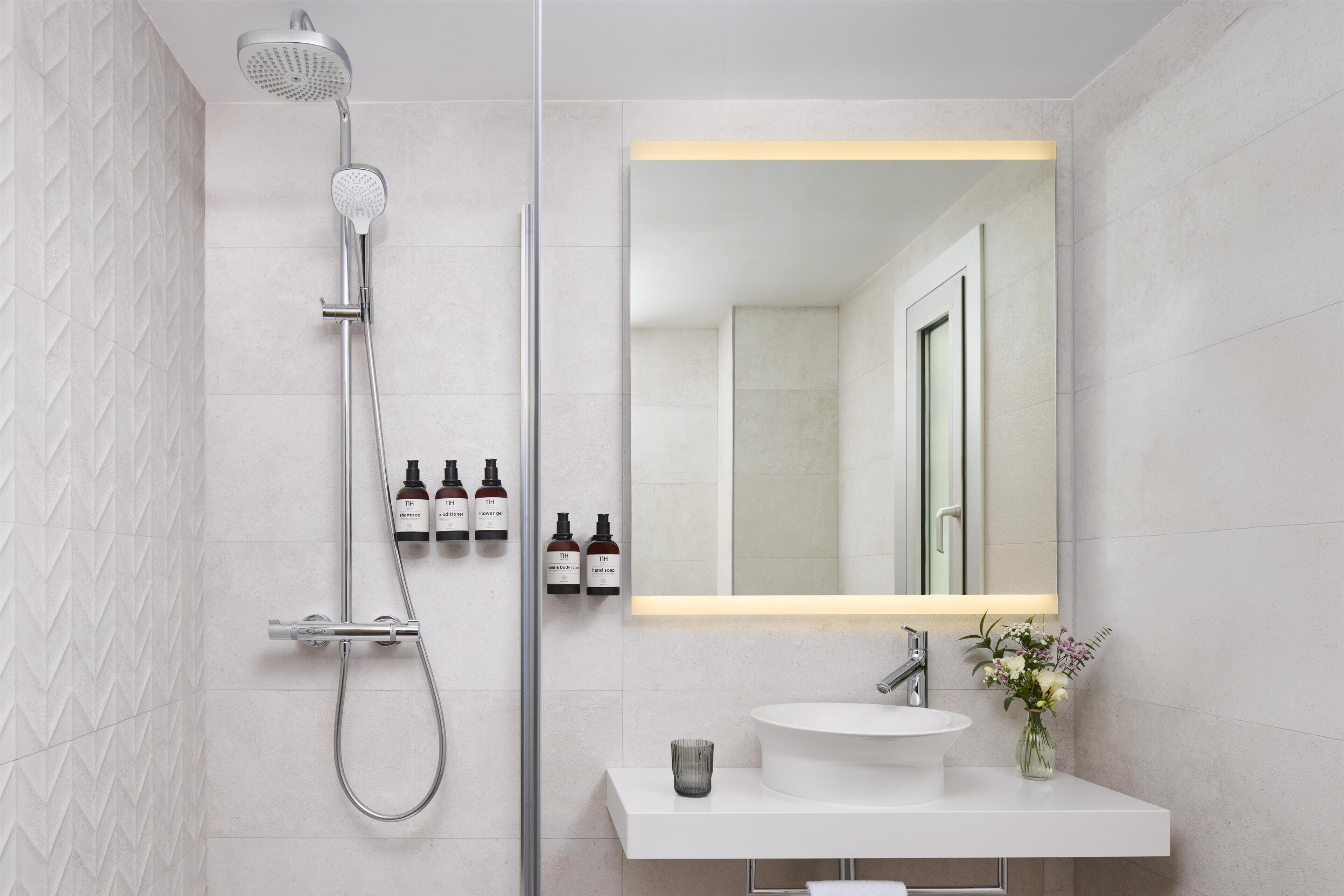 Een moderne badkamer met een douche, een grote spiegel en een wastafel.