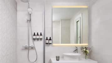 Een moderne badkamer met een douche, een grote spiegel en een wastafel.