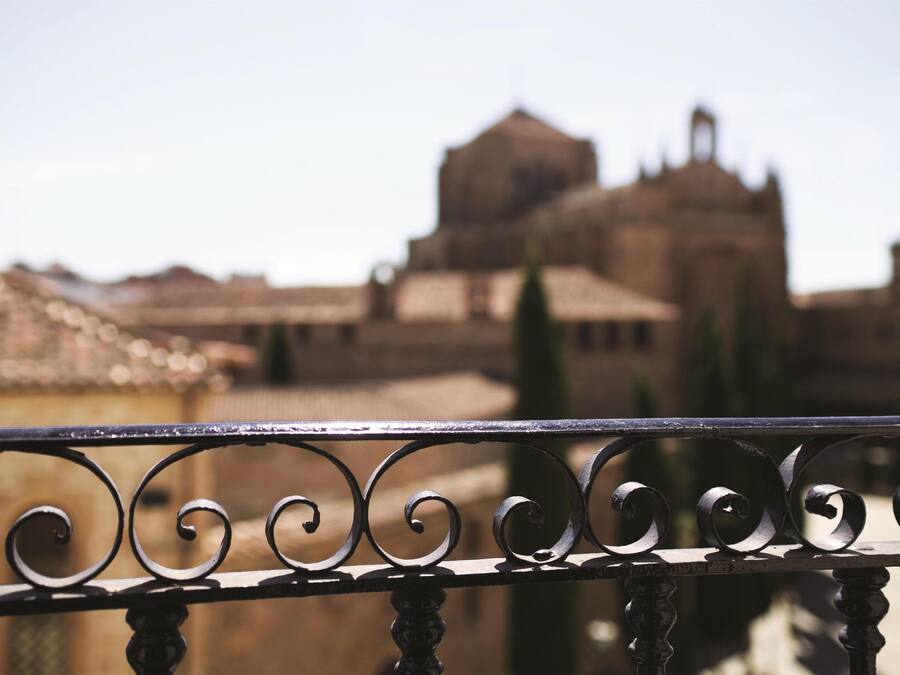 Vista de um edifício histórico com estrutura em cúpula e um campanário, vista através de um corrimão de metal.