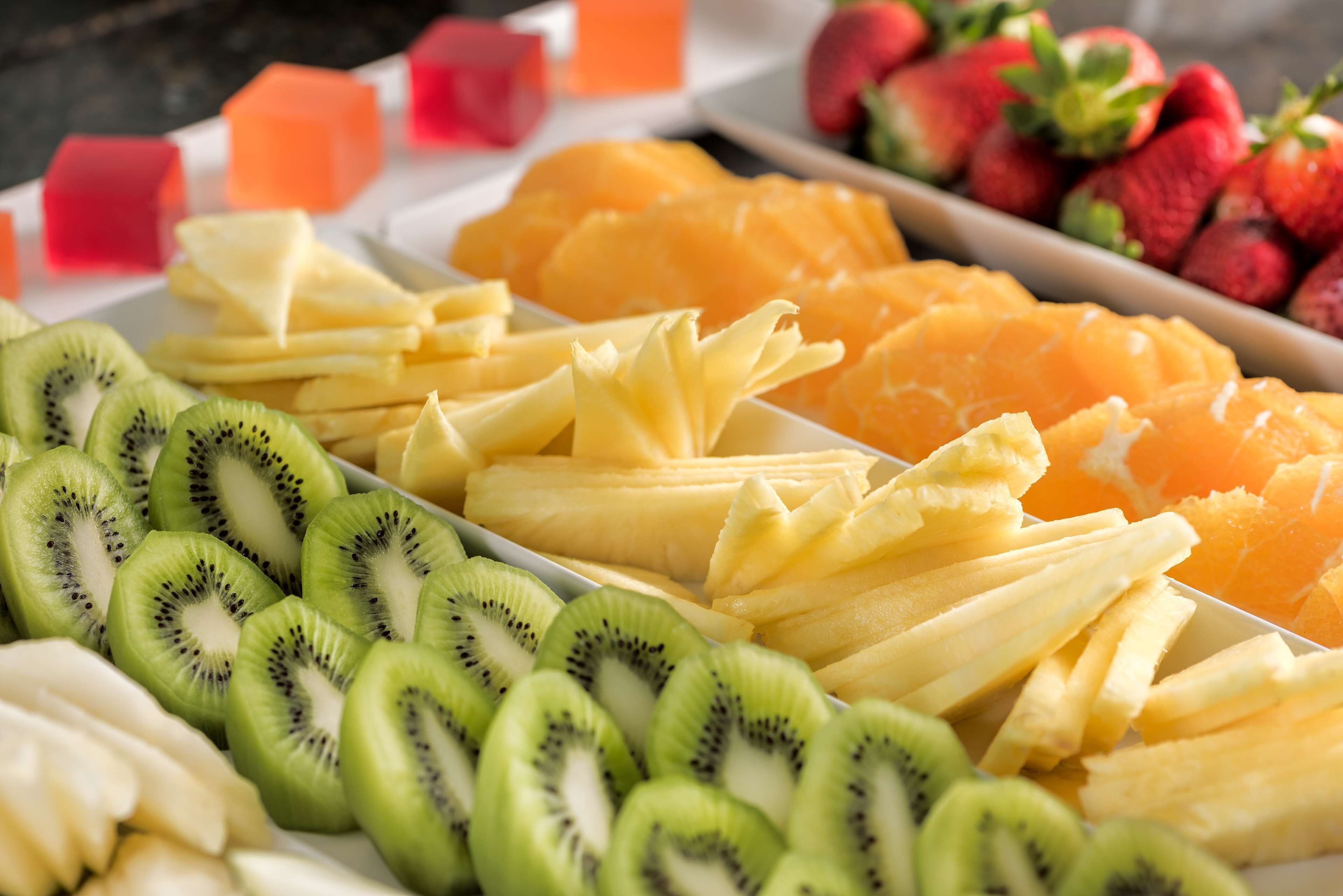 Une variété de fruits frais, notamment des tranches de kiwi, d’ananas et d’oranges, disposés sur un plateau.