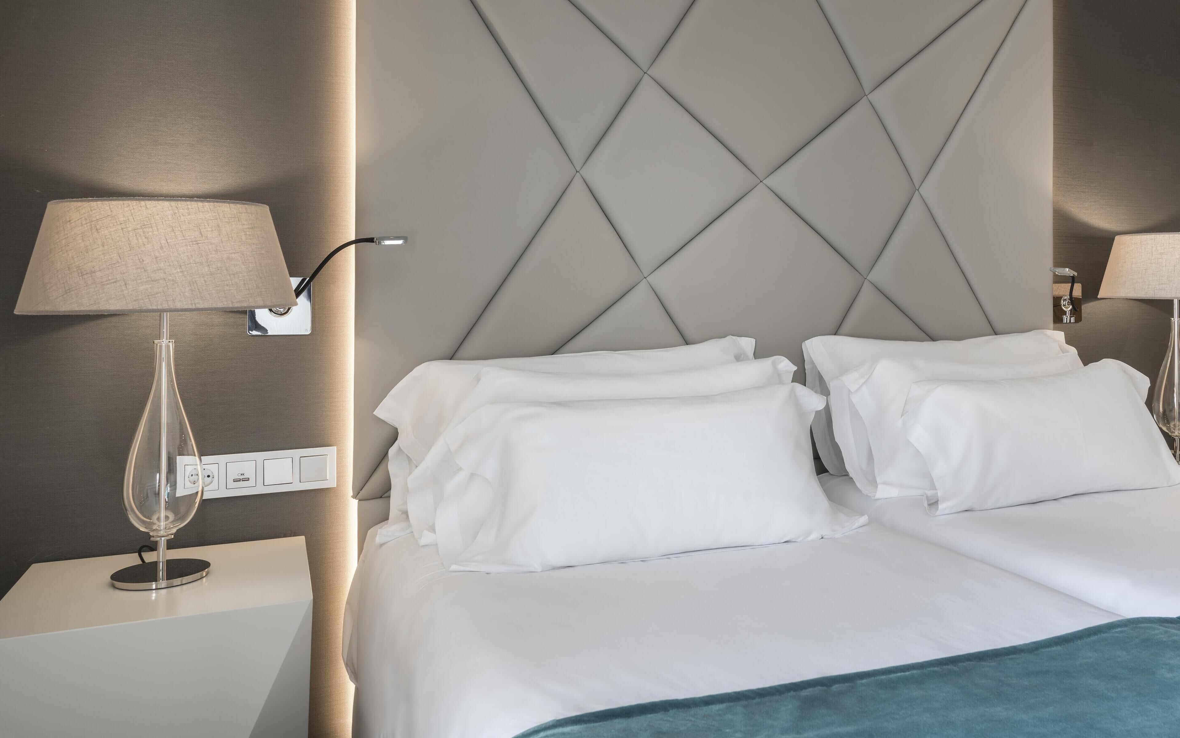 Une chambre d’hôtel avec un lit, deux lampes de chevet, une table de chevet et une lampe fixée au mur.