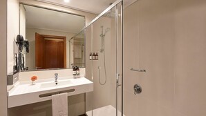 A modern bathroom with a glass shower enclosure, a vanity with a mirror, and a towel rack.