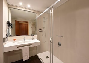 Een moderne badkamer met een douchecabine van glas, een wastafel met spiegel en een handdoekrek.