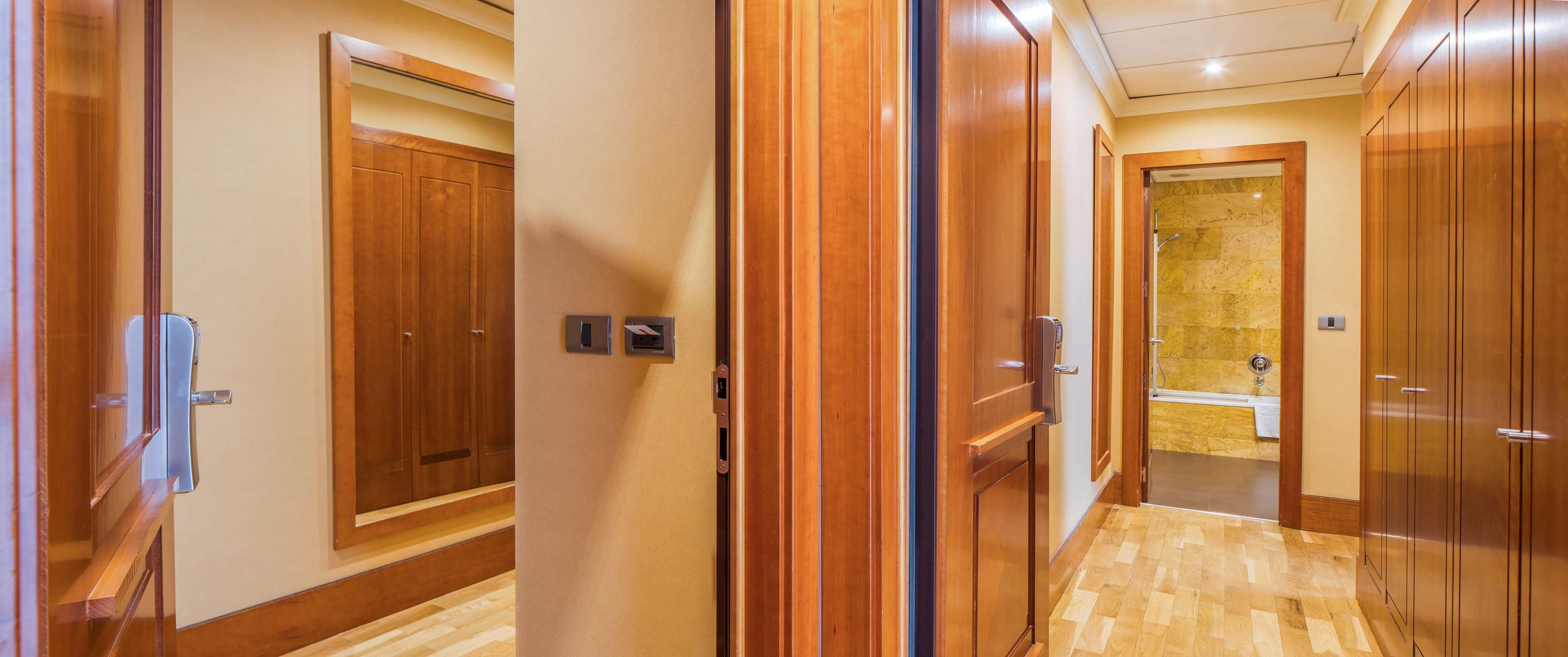 A hallway with wooden doors leading to a bathroom with a bathtub.