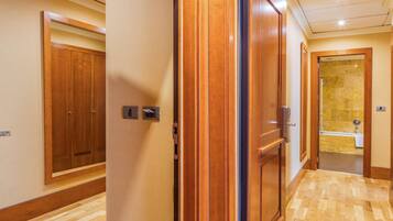 A hallway with wooden doors leading to a bathroom with a bathtub.