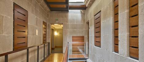 Un pasillo con piso de madera, paredes de piedra y tragaluz.