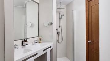 A modern bathroom with a shower, a sink with hand soap, and a mirror.