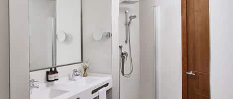 Un baño moderno con ducha, lavamanos y espejo.