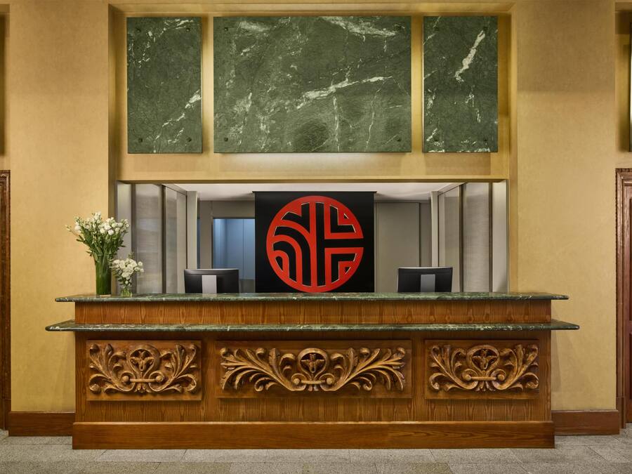 Una recepció amb una paret de marbre a dalt i un panell de fusta amb treballs de talla intricats a sota.