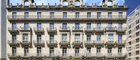 Un edificio de varios pisos con balcones ornamentados y una entrada central.
