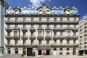 A multi-story building with ornate balconies and a central entrance.