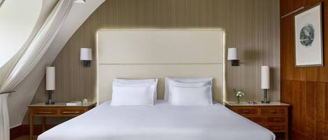 Habitación de hotel con una cama grande, dos mesitas de noche con lámparas, un cabecero de madera y un cuadro en la pared.
