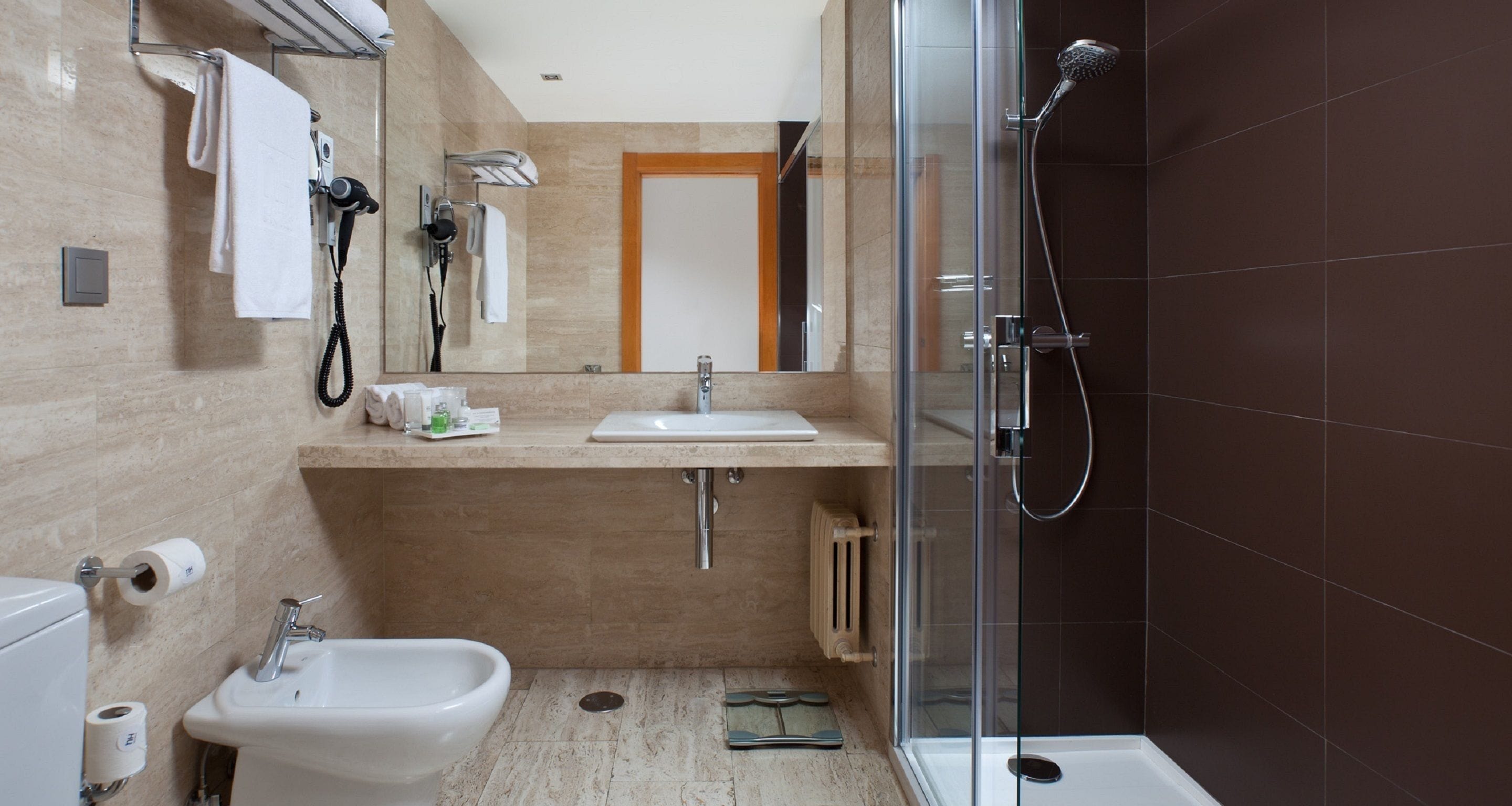 Une salle de bain moderne dotée d’une douche à parois de verre, d’un lavabo et d’un bidet.