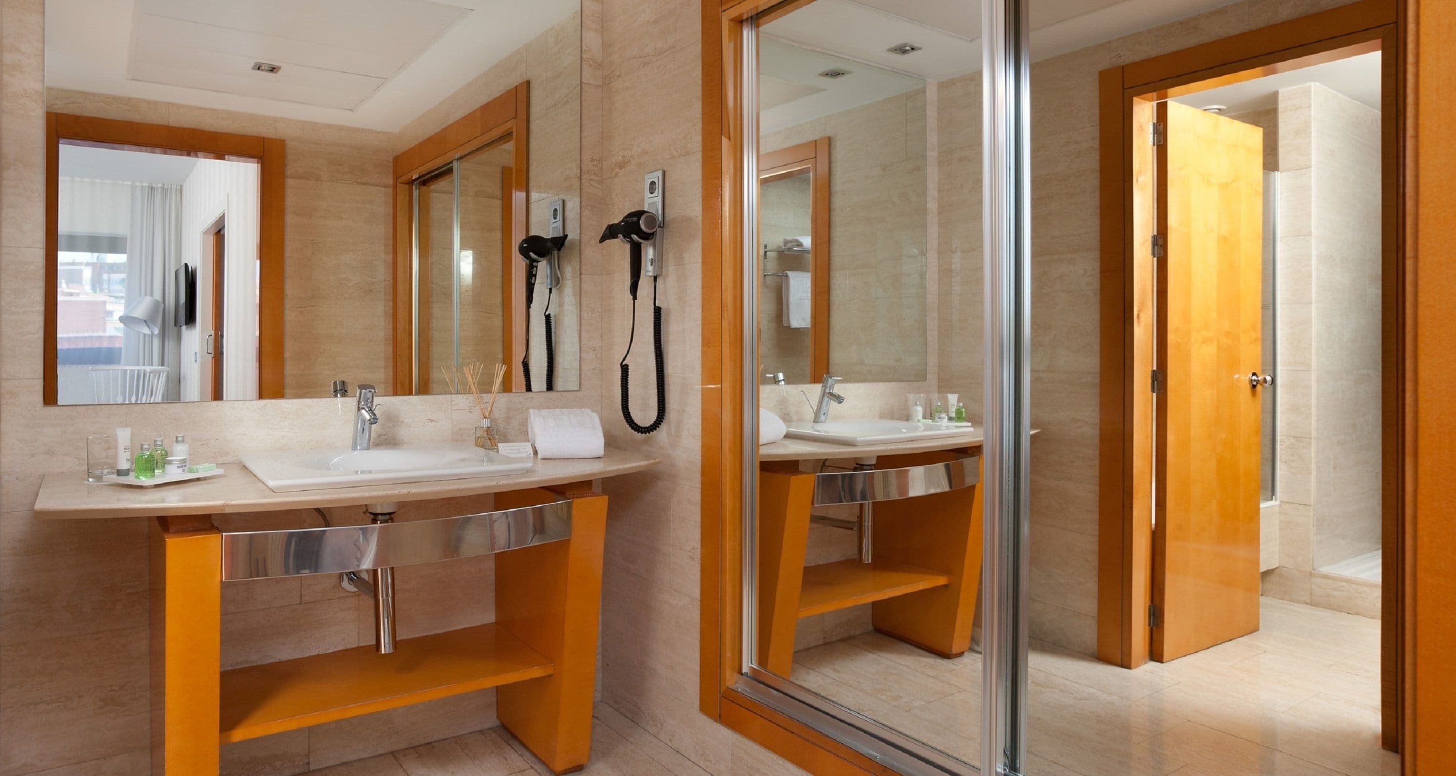 Un baño moderno con dos lavamanos, un espejo grande y un secador de pelo.