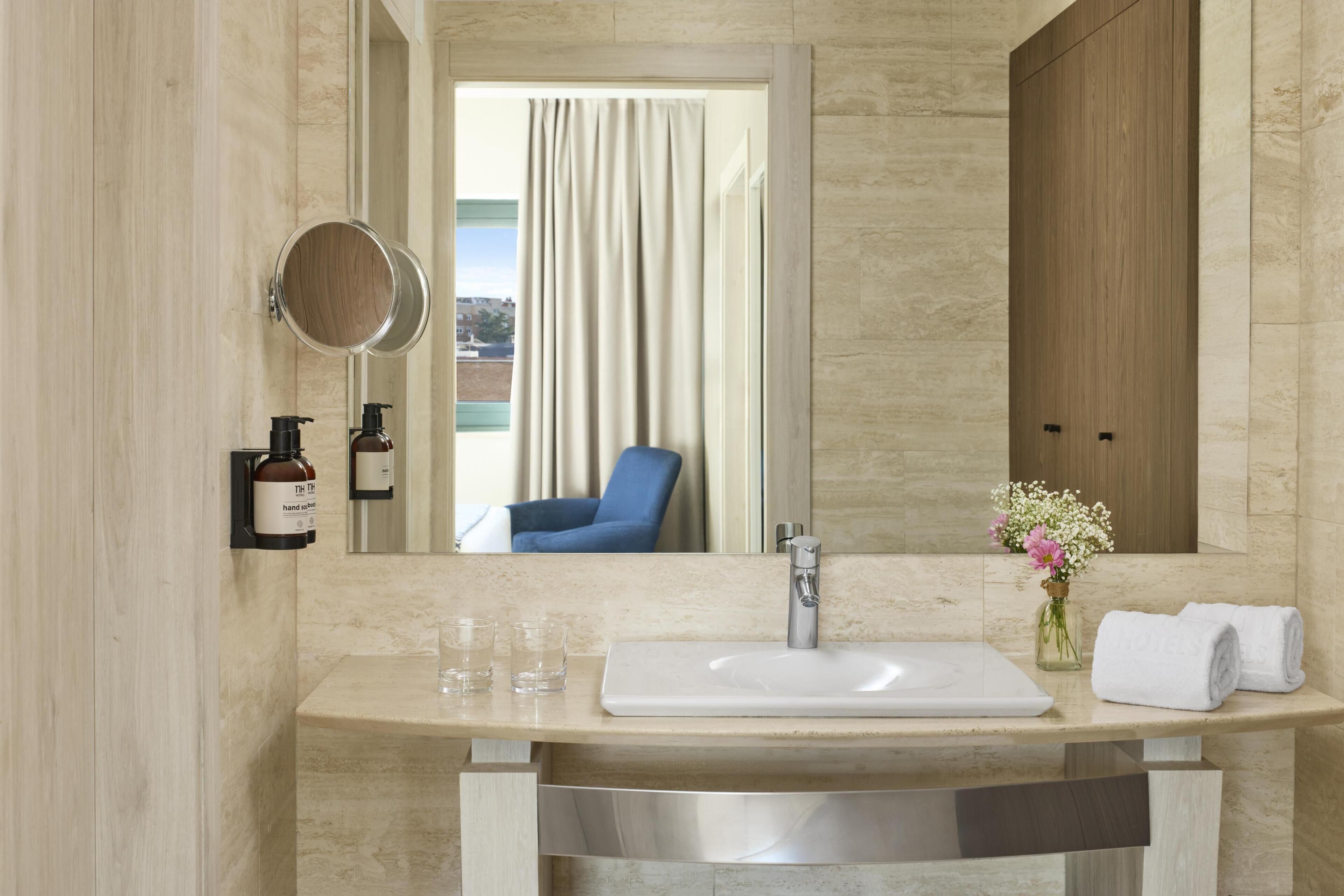 A bathroom with a large mirror, a sink, and a towel rack.