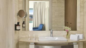 A bathroom with a large mirror, a sink, and a towel rack.
