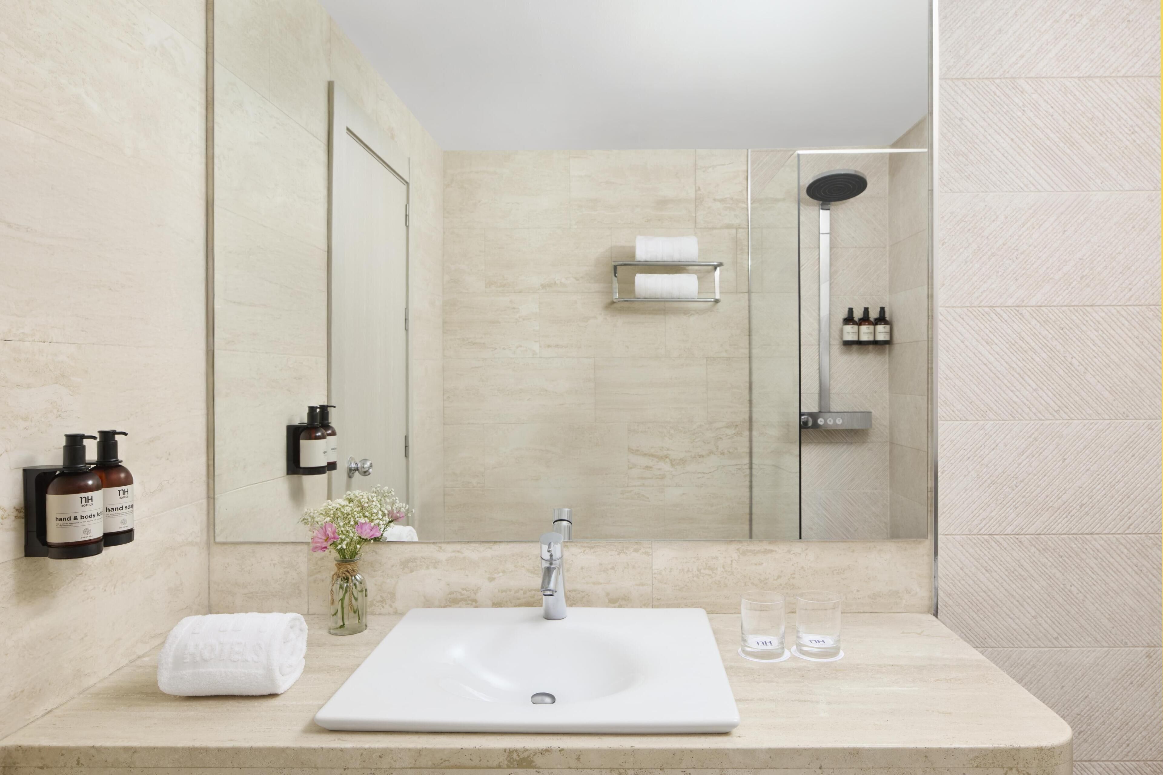 Un baño moderno con un espejo grande, un lavamanos y una ducha.