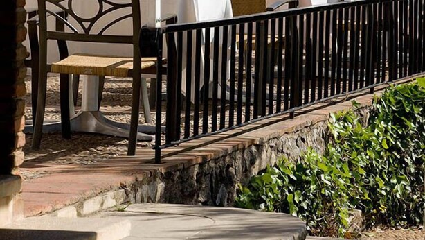A white building with a balcony, wooden chairs, and tables. - La Perdiz (La Carolina)