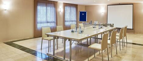A conference room with a long table, chairs, a projector screen, and a whiteboard.