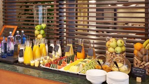 Un bufé de desayuno con diversas frutas, zumos y bebidas embotelladas.