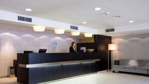 Un comptoir d’accueil moderne, avec une réceptionniste, un canapé et une lampe.