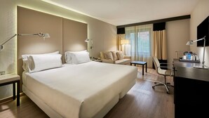 Une chambre d’hôtel avec un grand lit, un bureau, une chaise, une petite table et un canapé.