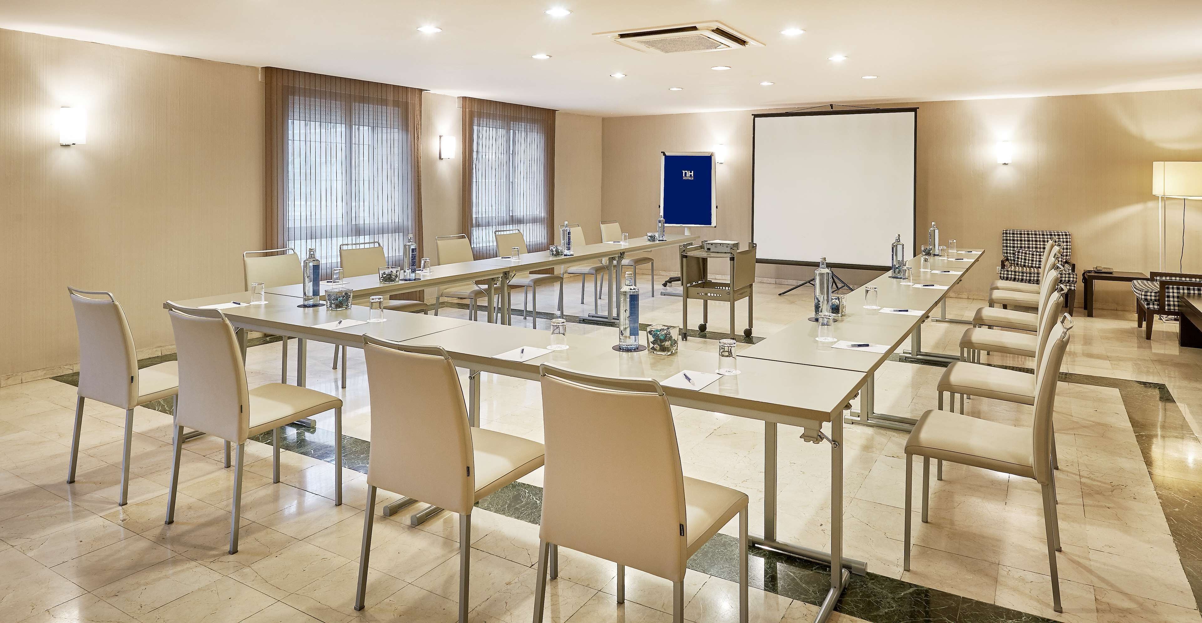A conference room with a long table, chairs, a projector screen, and a whiteboard.