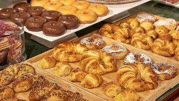 A variety of pastries including chocolate-covered donuts, croissants, and other baked goods displayed on wooden boards.