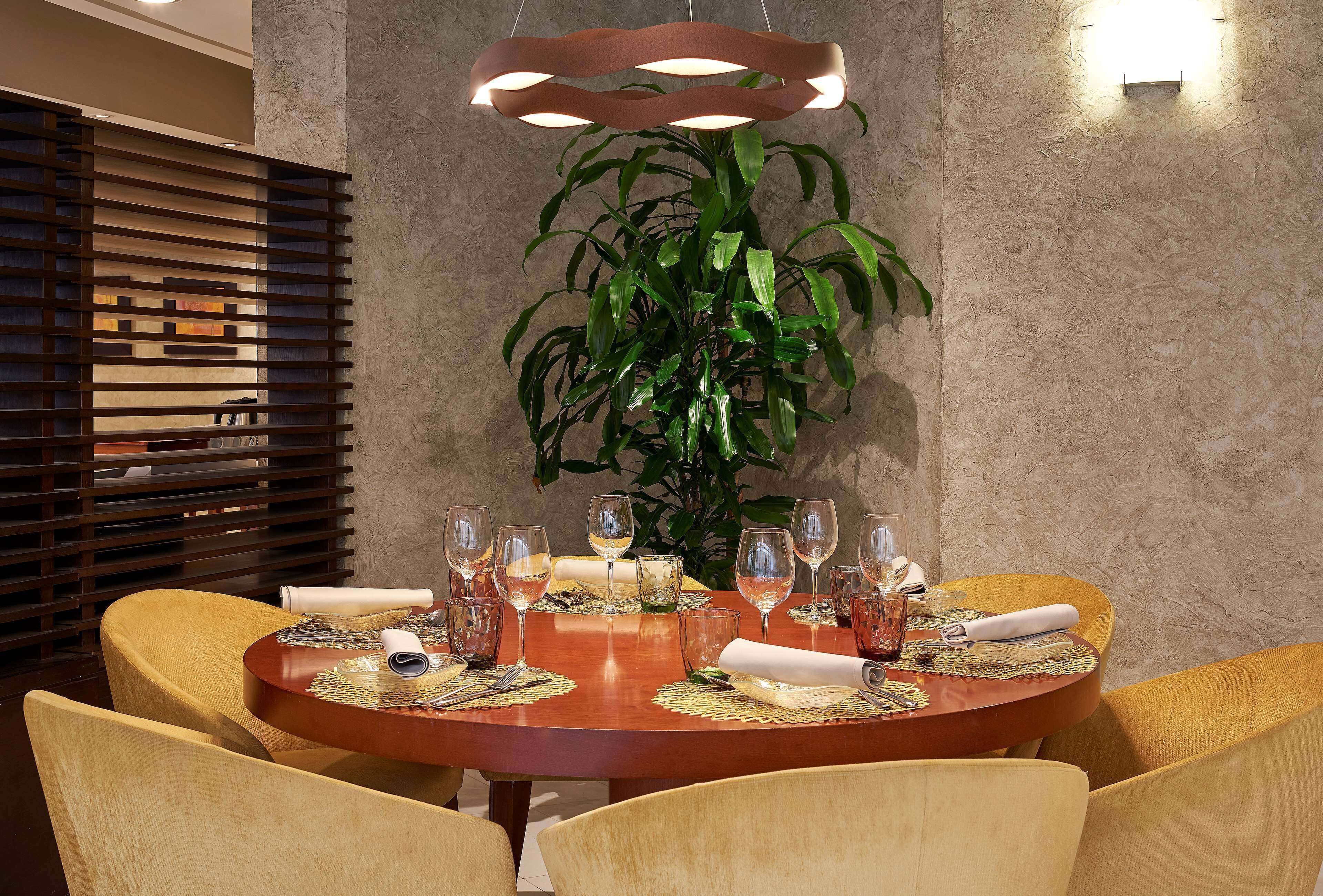 A dining area with a round wooden table set for six, surrounded by yellow chairs.