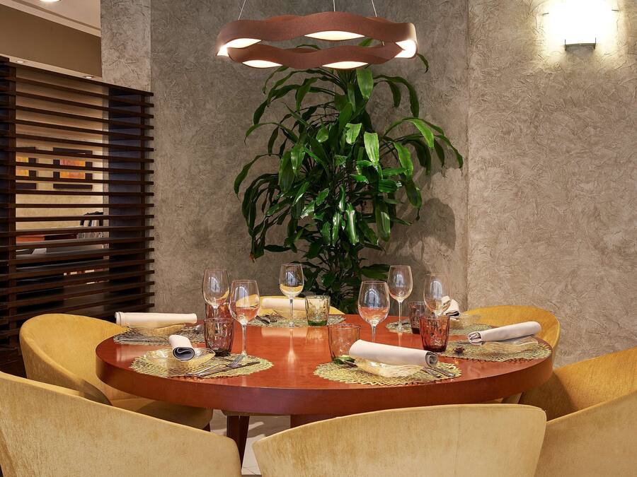 A dining area with a round wooden table set for six, surrounded by yellow chairs.