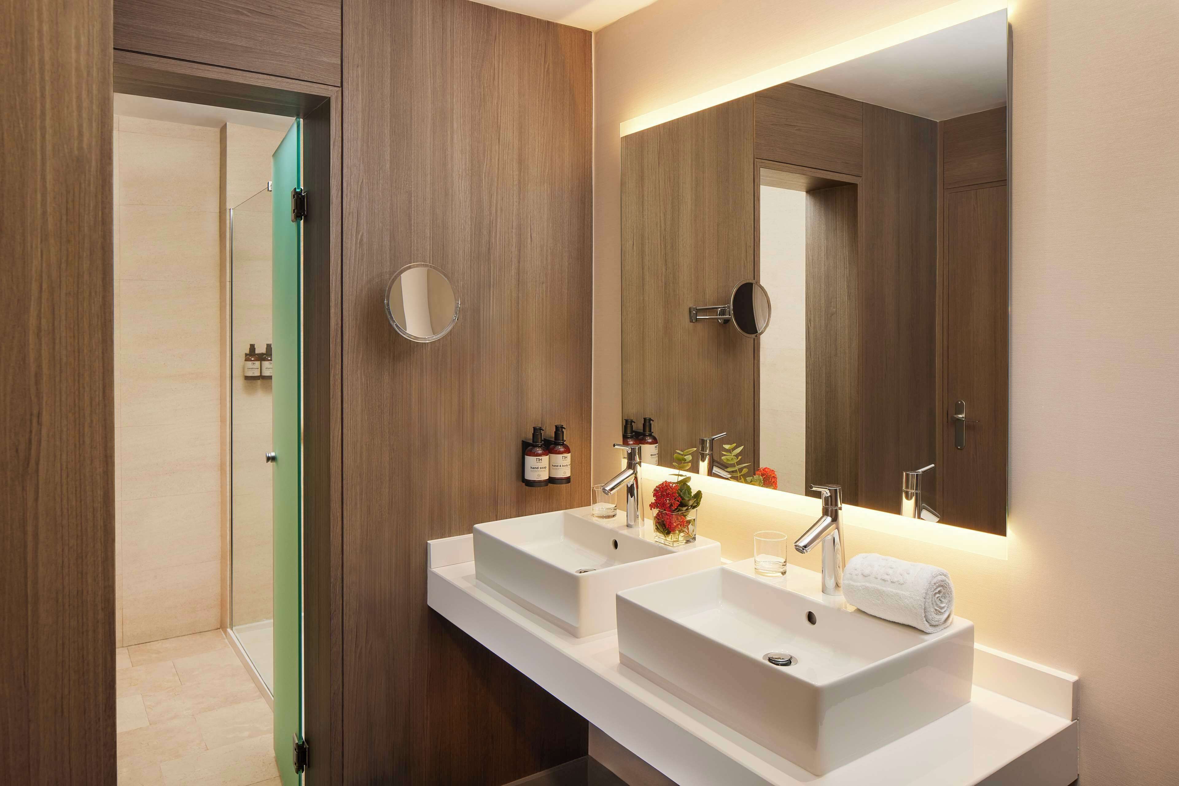 Un baño moderno con dos lavamanos, un espejo grande y una puerta verde que da a la zona de ducha.