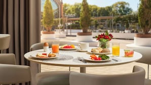 A breakfast table set with plates of food, drinks, and a vase of flowers.