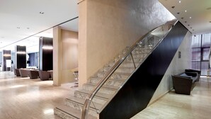 A modern interior with a curved staircase, marble flooring, and contemporary furniture.