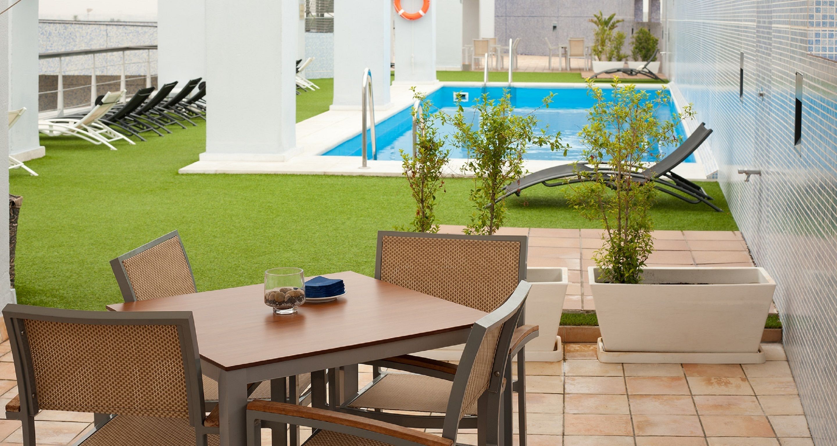 A patio with a pool, outdoor seating, and a view of the pool area.