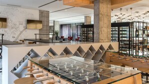 A modern lobby with a foosball table, bar stools, and a checkered floor.