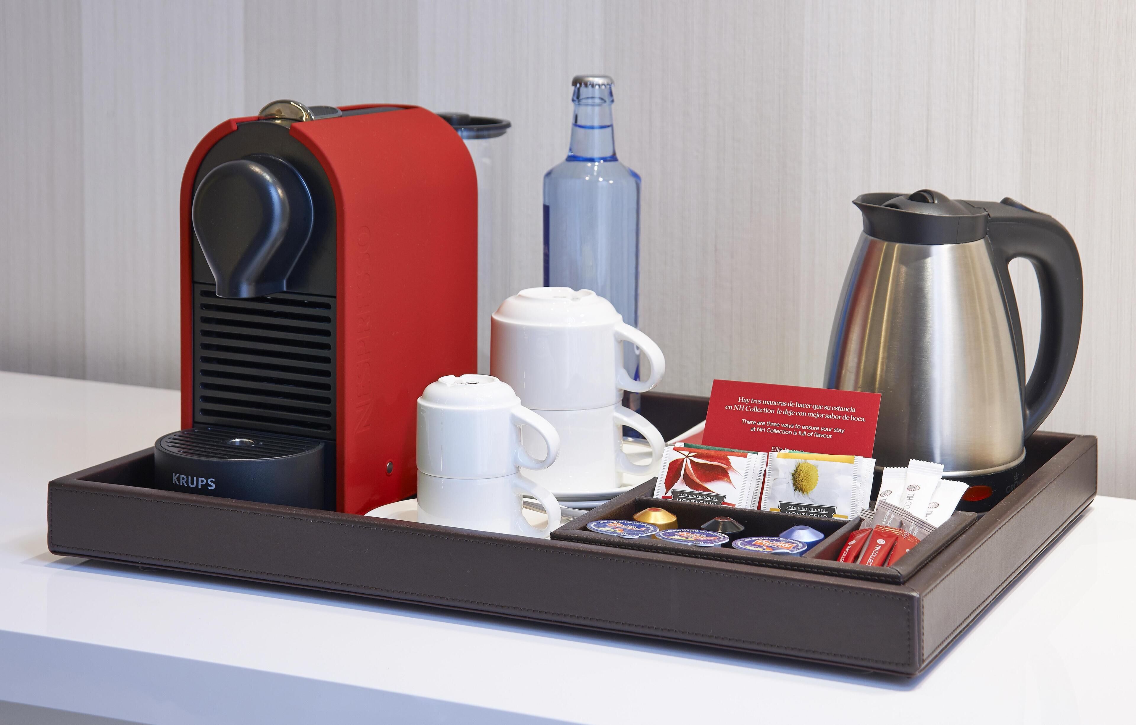 A tray with a coffee maker, a water bottle, a coffee pot, a mug, and a card with text.