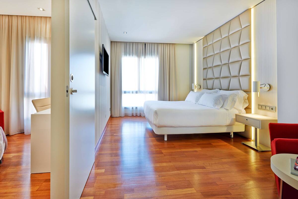 Una habitación de hotel con una cama, un escritorio, una silla y un televisor.