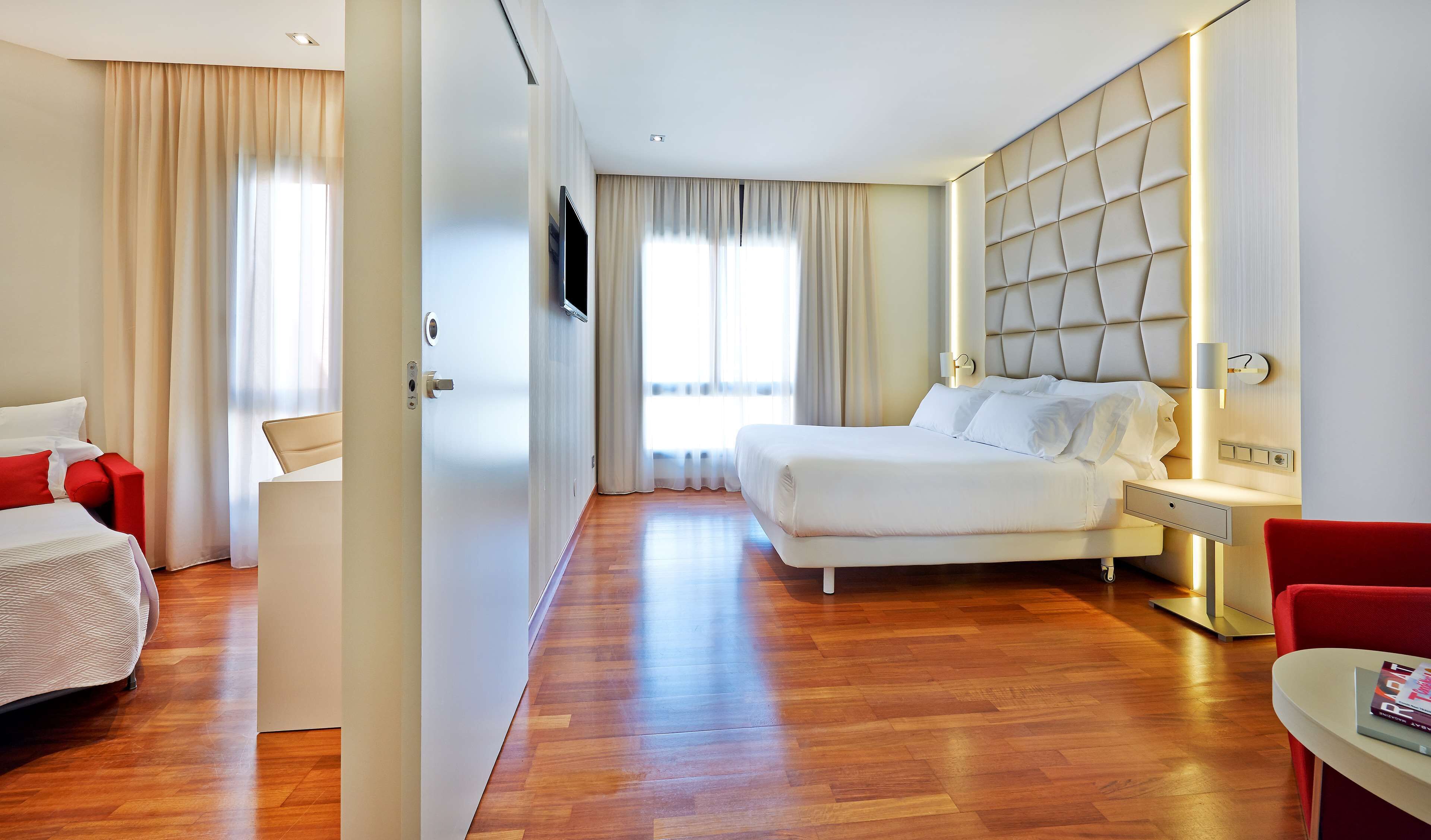 A hotel room with a bed, a desk, a chair, and a TV.