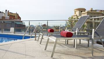 Una piscina al aire libre, sombrillas, tumbonas