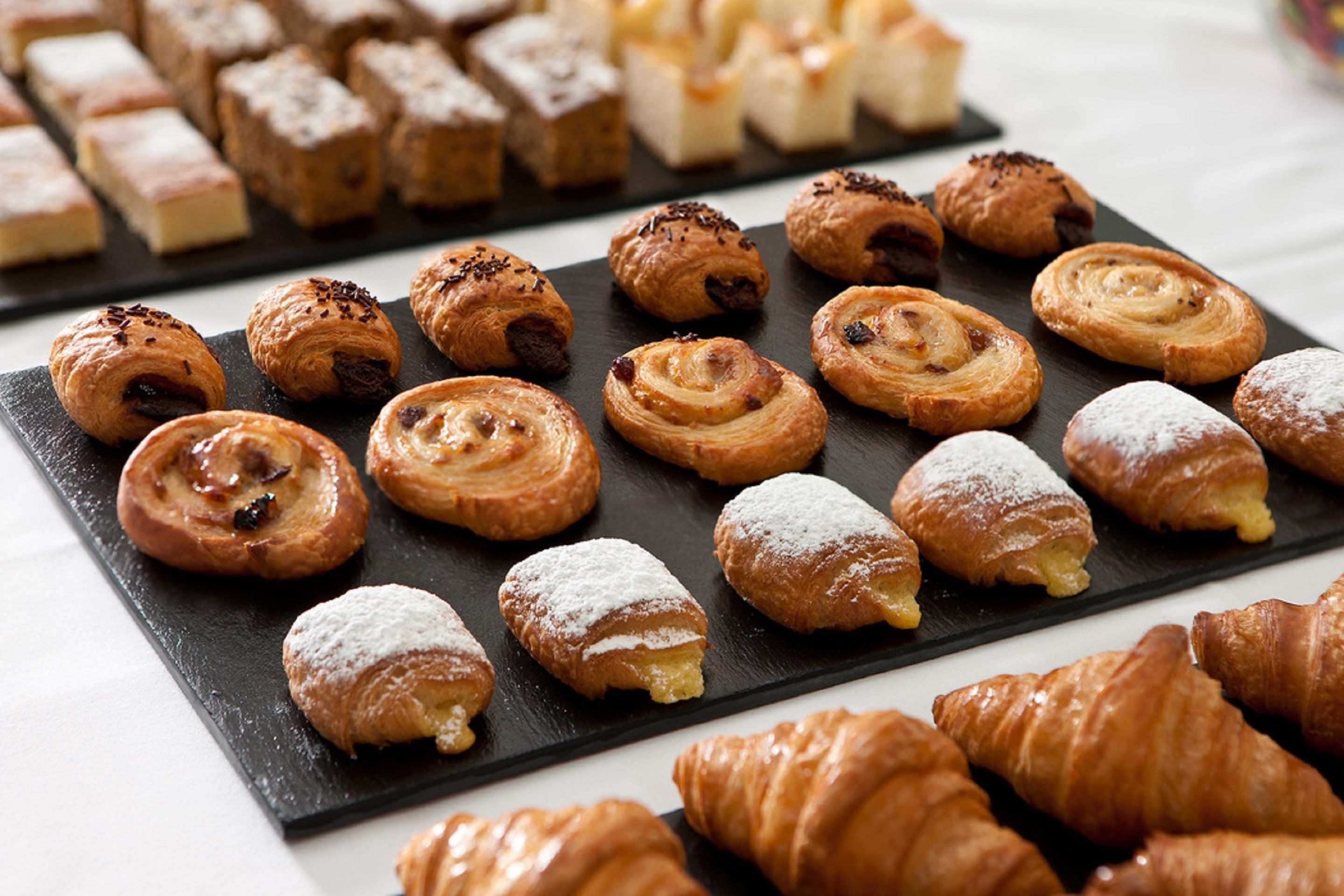Ett urval av bakverk på en skifferbricka, inklusive croissanter och andra sorters bakelser.