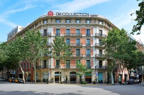 Un hotel de varios pisos con un estilo arquitectónico europeo clásico, que cuenta con balcones y una entrada central.