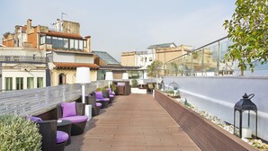 Eine Dachterrasse mit Korbmöbeln und einer weißen Brüstung.