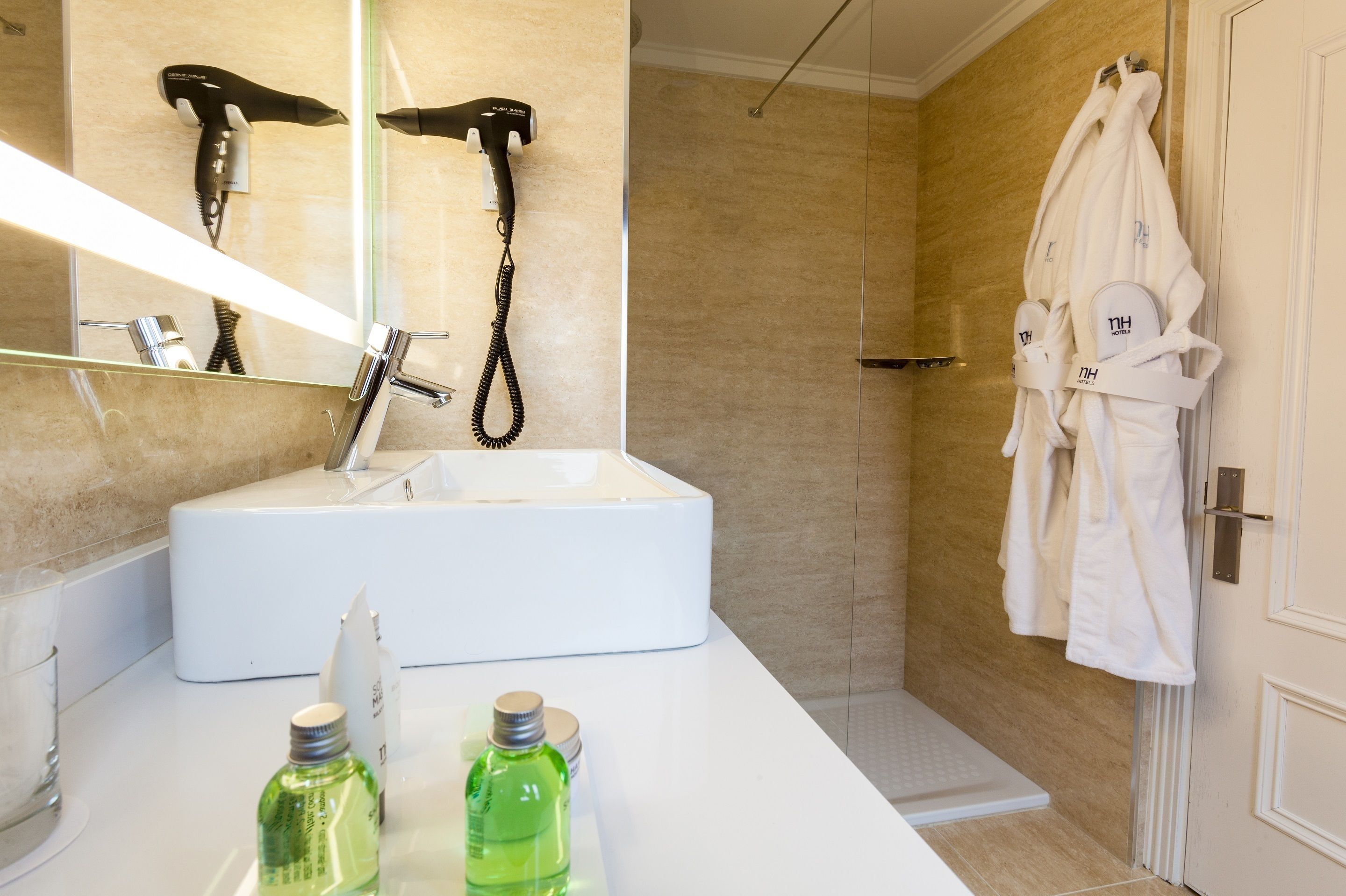 Ein modernes Badezimmer mit einem weißen Waschbecken, einer Duschkabine aus Glas und einem Bademantel, der an der Wand hängt.