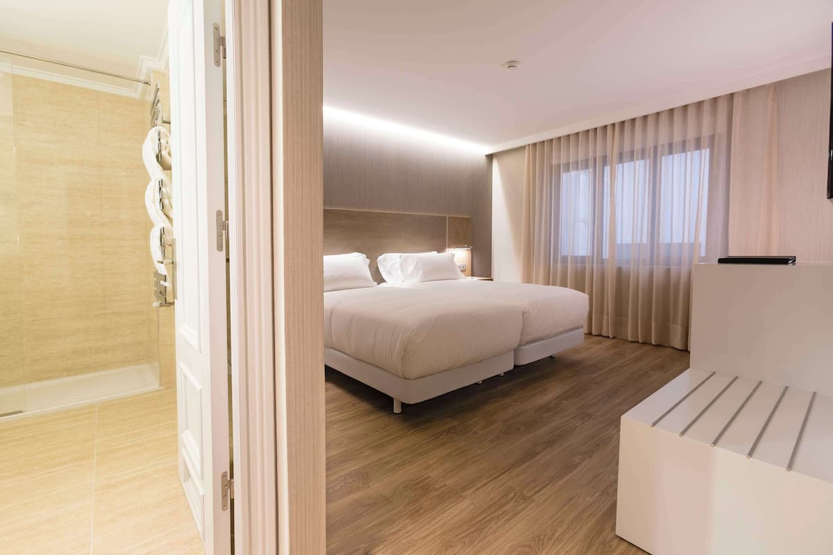 Ein modernes Hotelzimmer mit einem großen Bett, einem Nachttisch und einer Duschkabine.