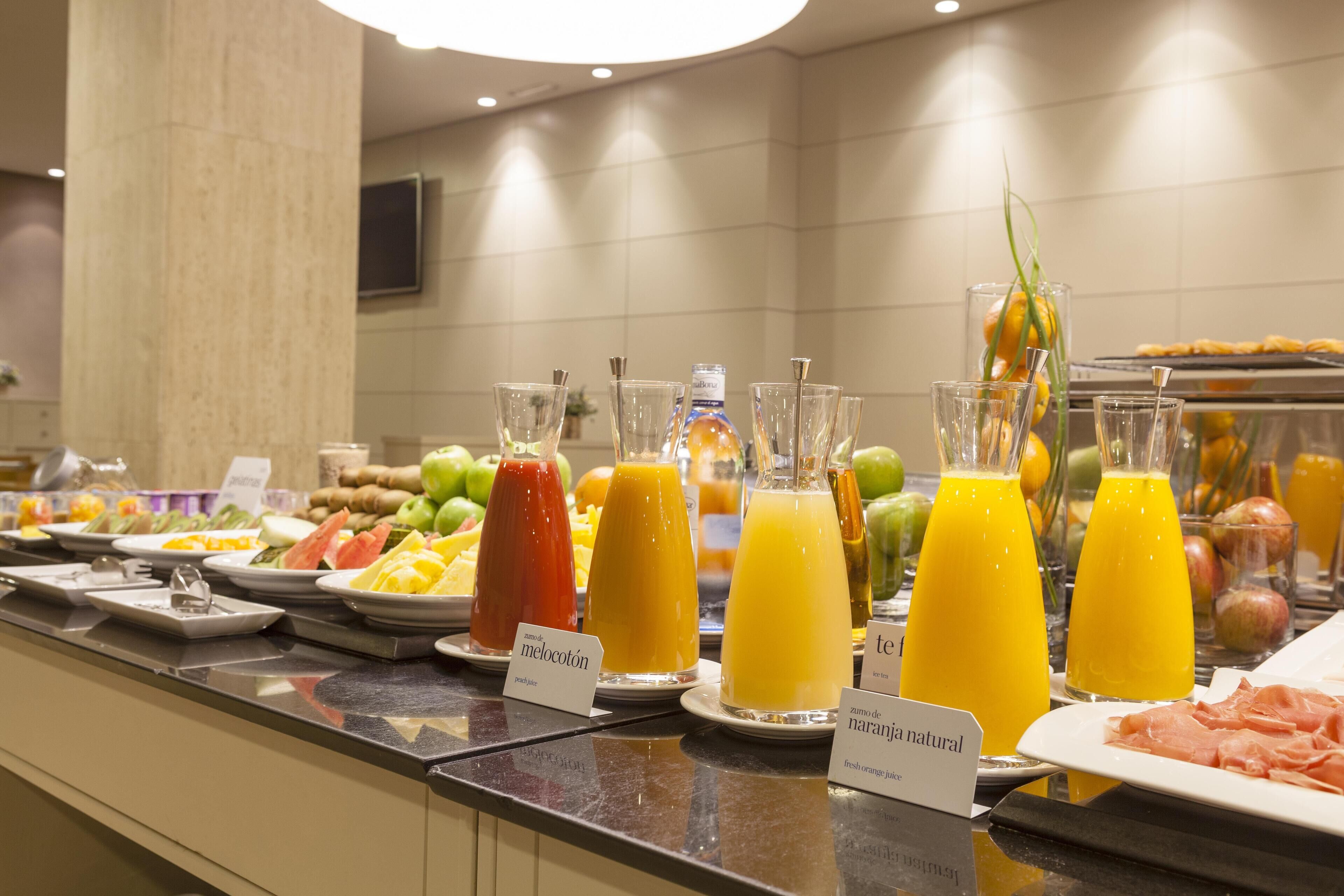 A buffet with various fruit juices and a selection of meats.