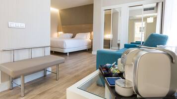 Et moderne hotelværelse med seng, bænk, siddeområde med bord og kaffemaskine.