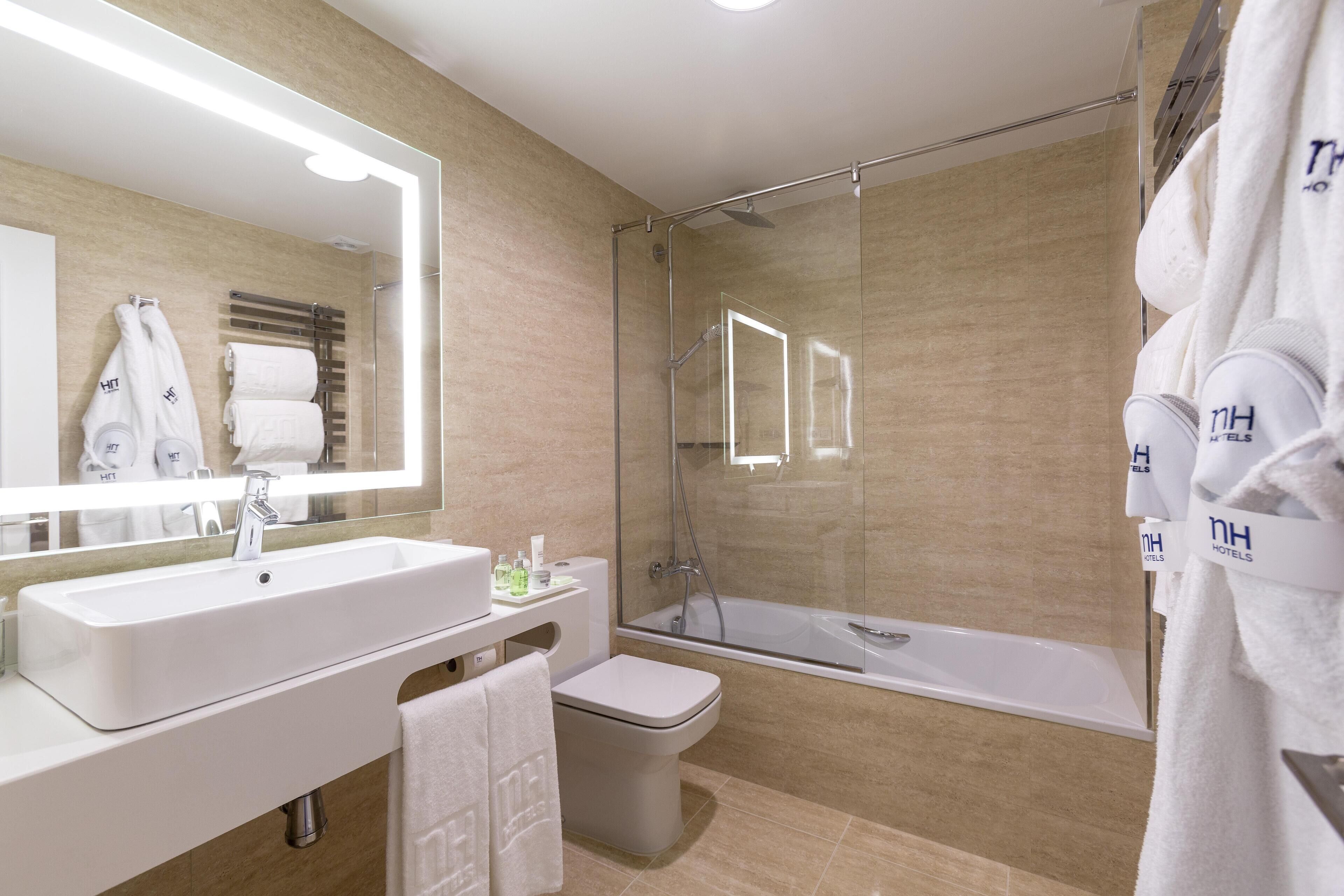 Un baño moderno con un espejo grande, un lavamanos, un inodoro y una ducha con cerramiento de vidrio.