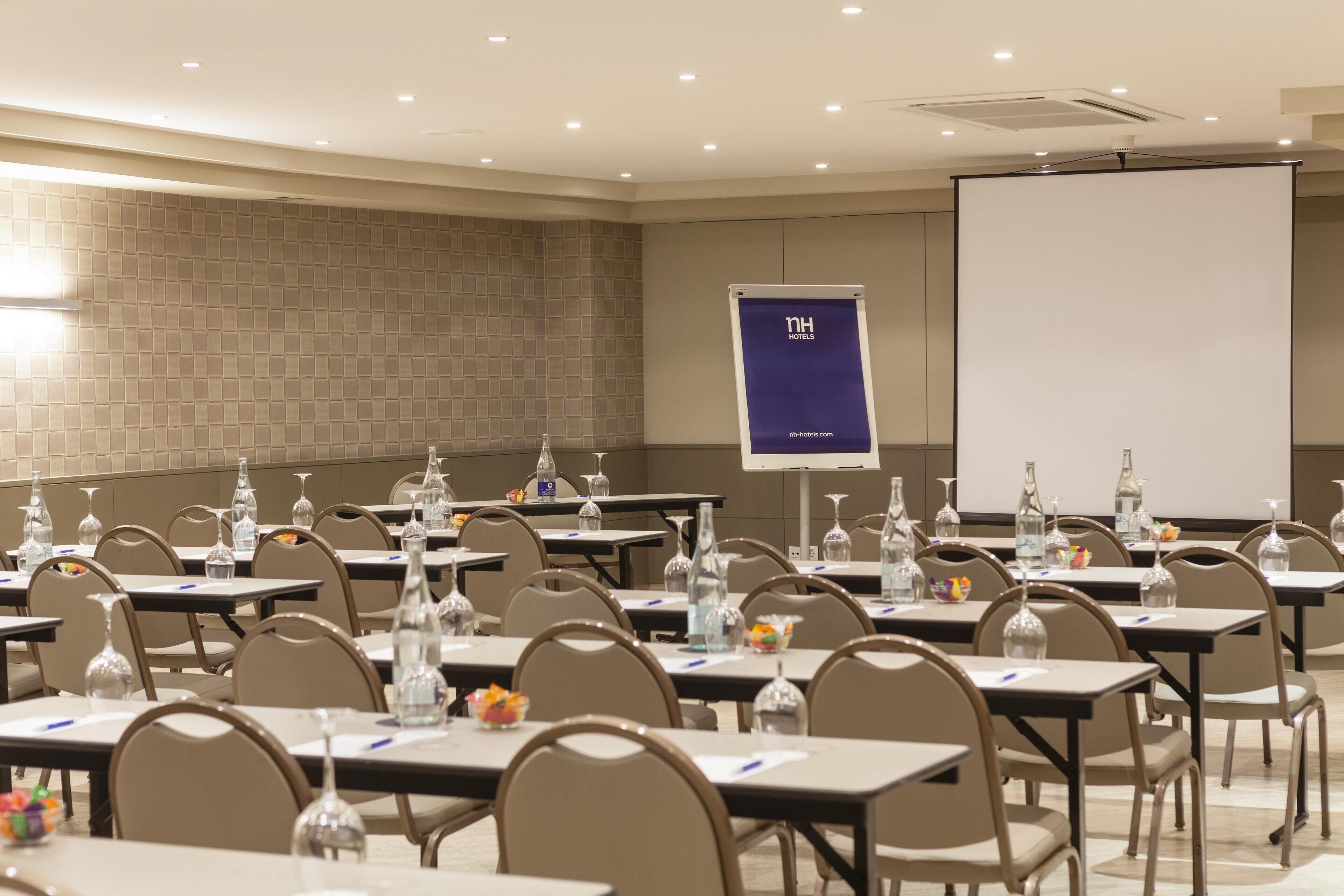 A conference room with tables, chairs, and a projector screen.