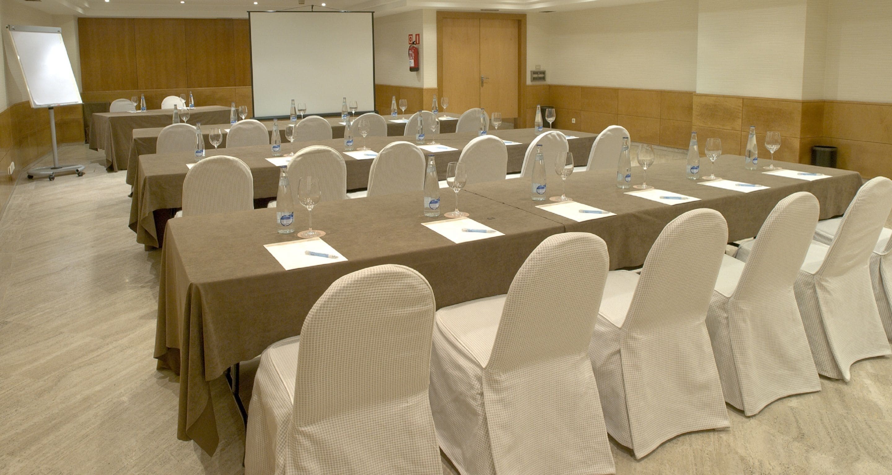 A conference room with multiple tables, chairs, and a whiteboard.